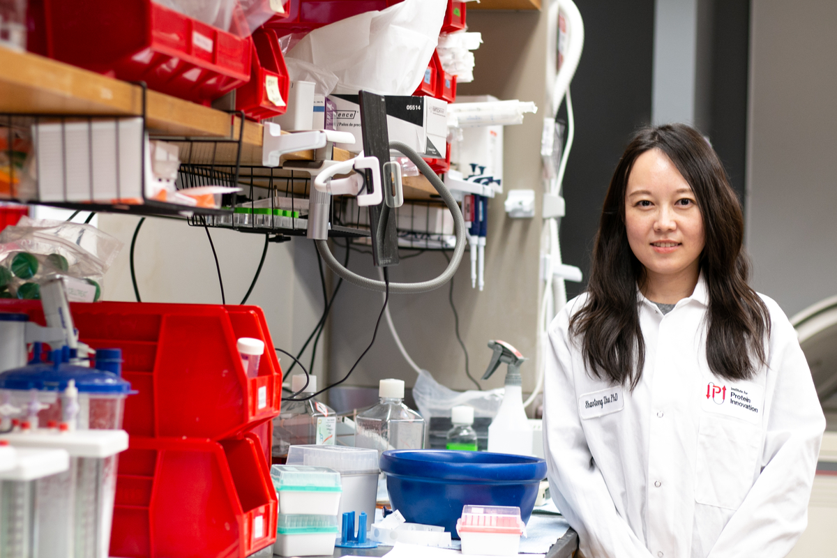 Shaotong Zhu in lab coat standing at IPI lab bench.