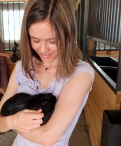 A young woman holds a bunny in an Amish barn.