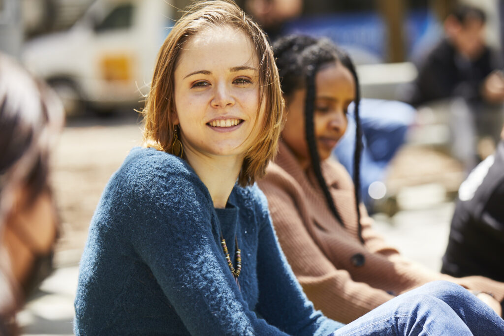 Woman wearing sweater sitting outside with group.