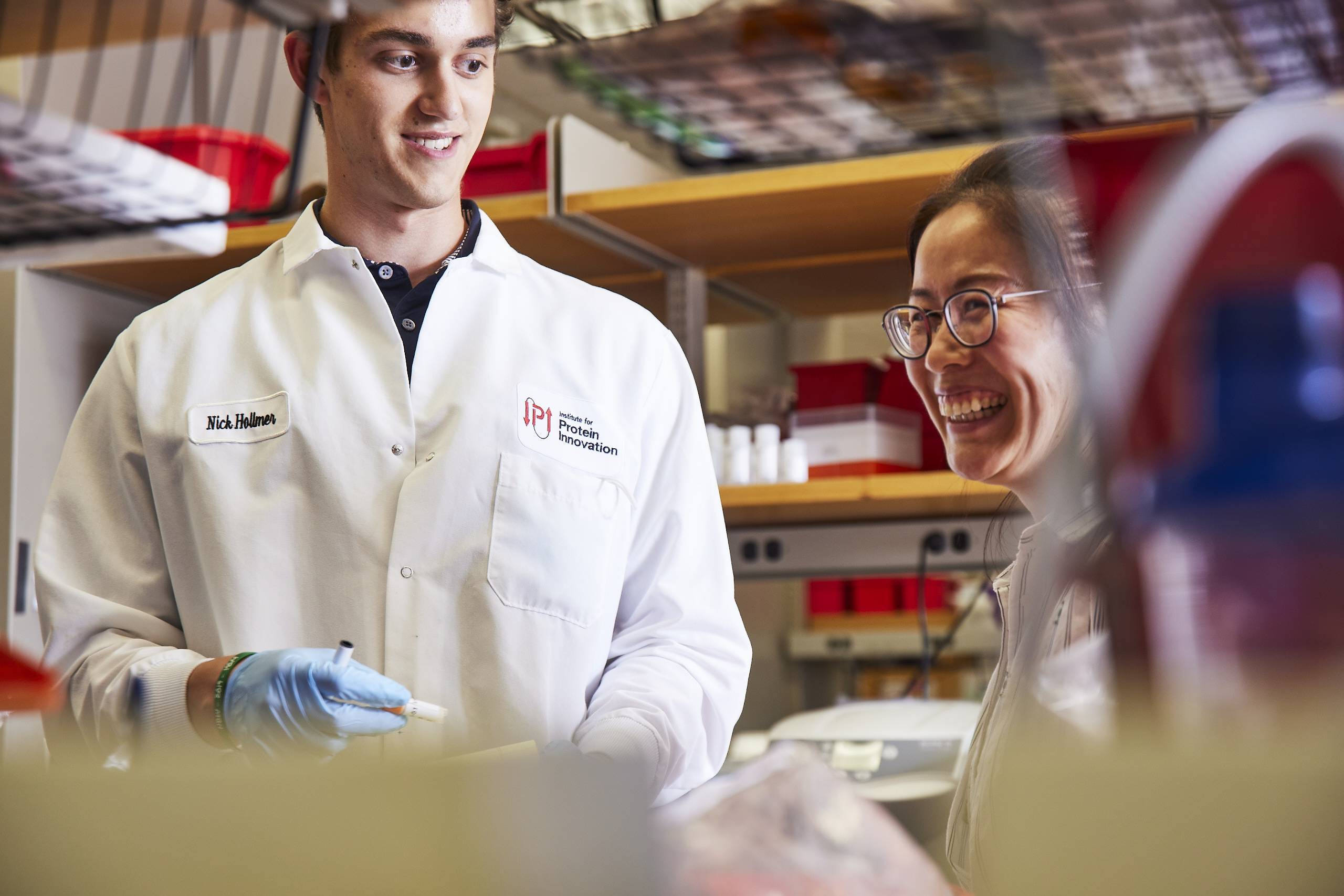 Two scientists in lab coats laughing.