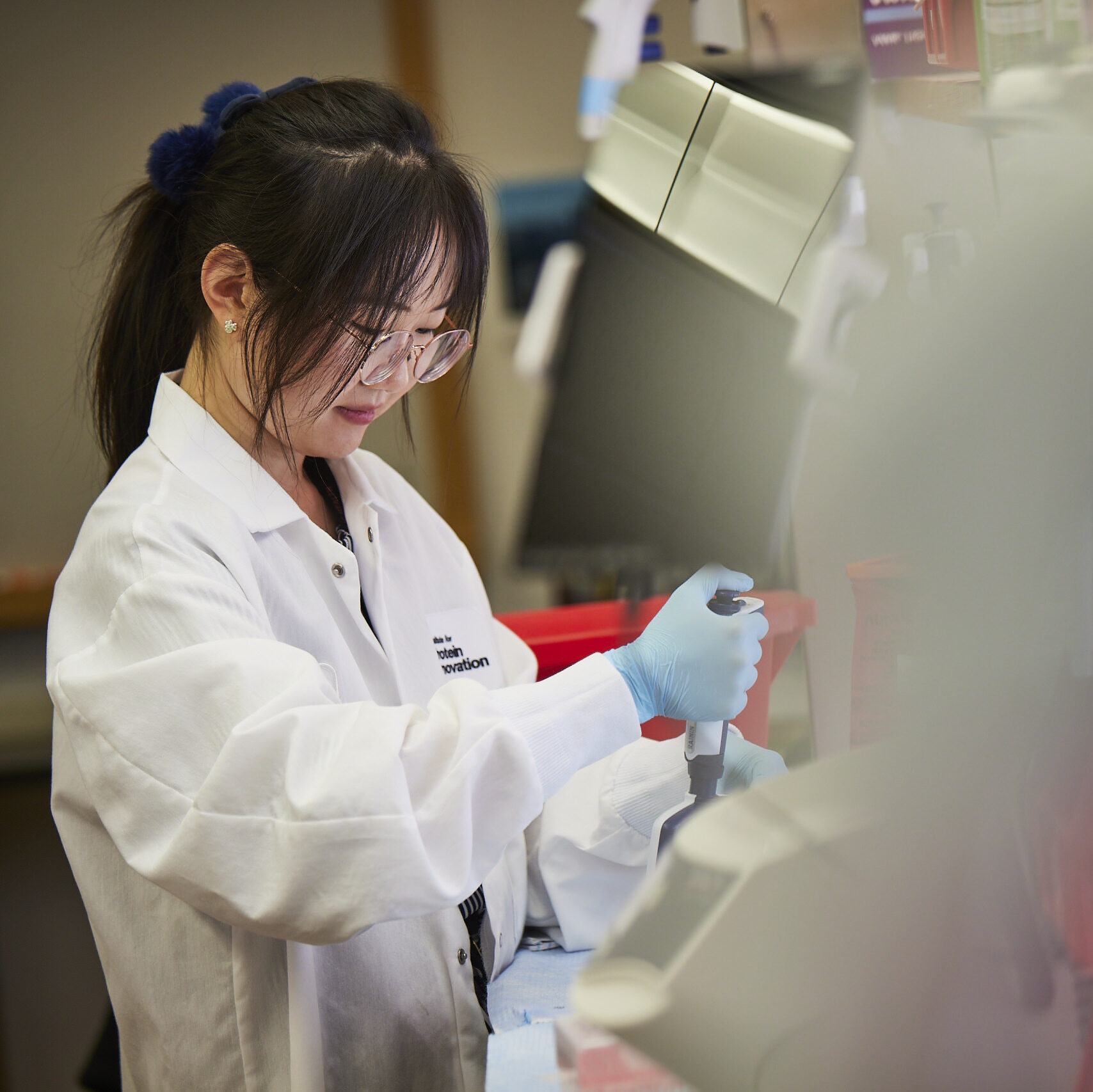 Woman in lab coat with pipettes