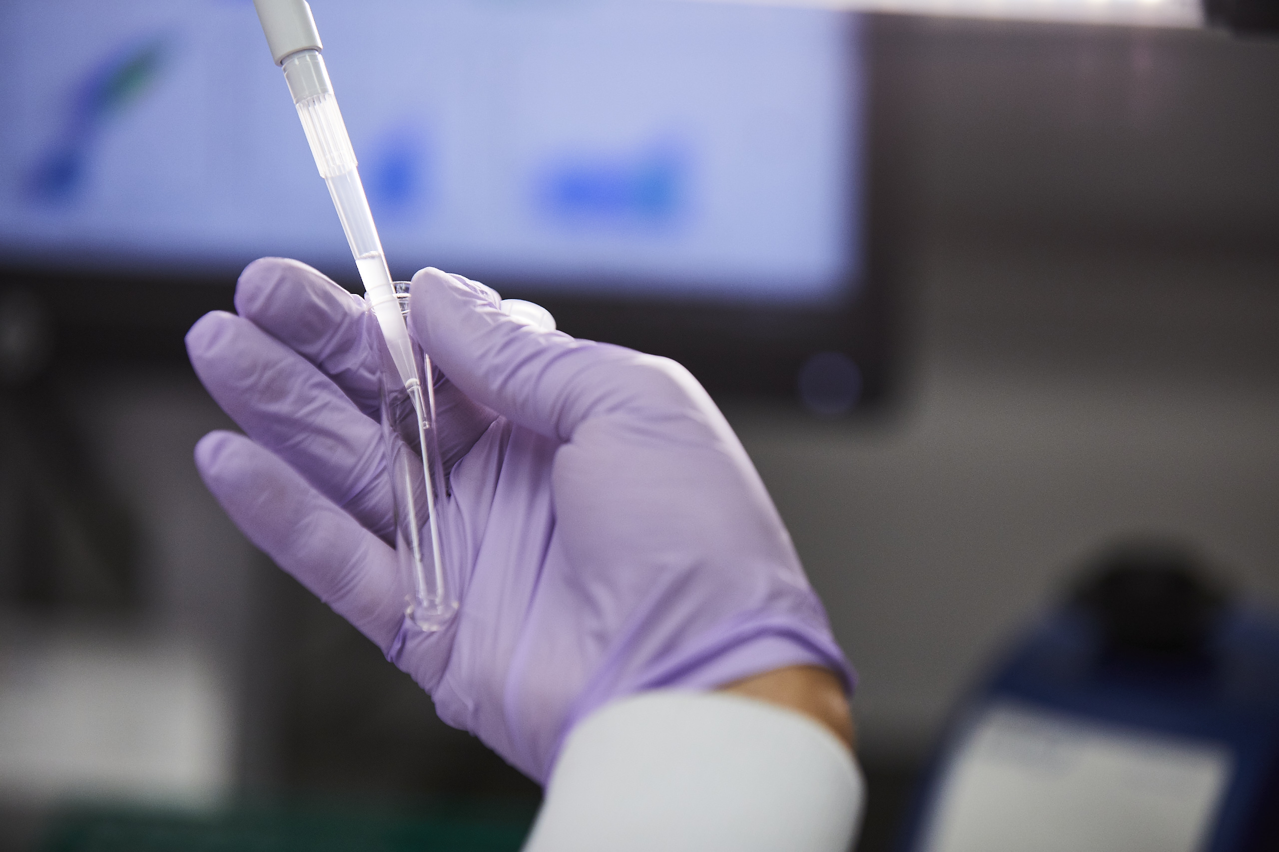 Hand holding pipette and tube.