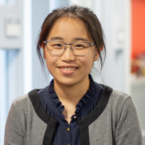 Miriam Li wearing glasses and smiling in office.