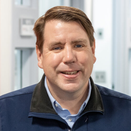 Man smiles for headshot in office.