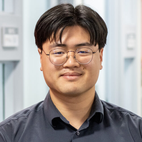 Man smiles in office, posing for headshot.