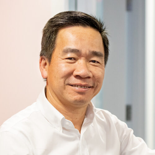 Hoan Nguyen, wearing a professional button-up shirt, smiles in the IPI office.