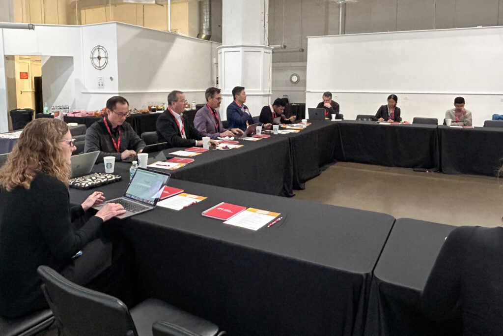 10 researchers sit around a u-shaped table, with notes and laptops out.