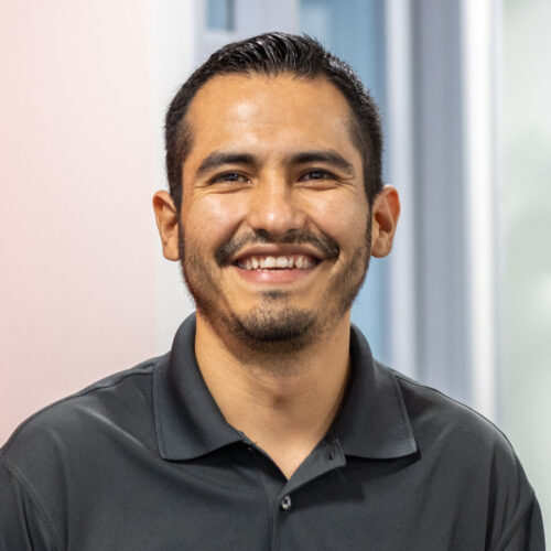 Eloy Salinas, wearing a black collared shirt, smiles in the IPI office.