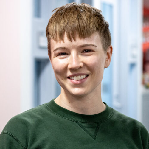 Leo Fletcher, wearing a green sweater, smiles in the IPI office.