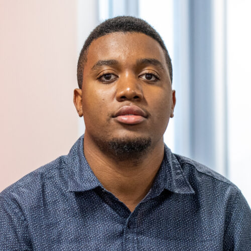 Marcus Sandaire, wearing a blue collared shirt, smiles in the IPI office.