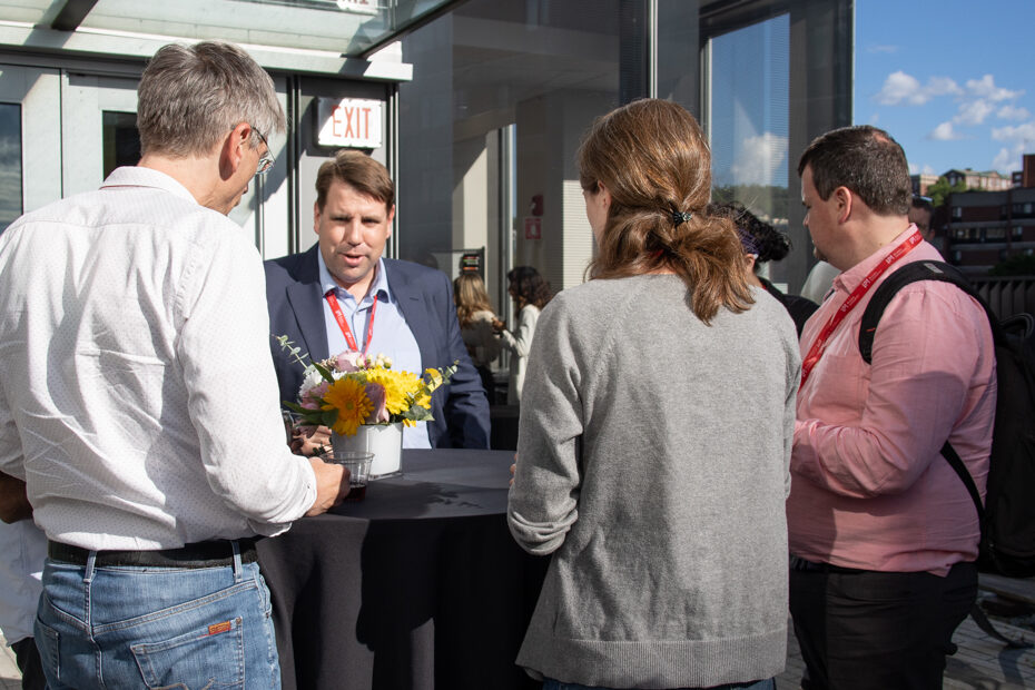 A group of conference attendees gather around a table outside.