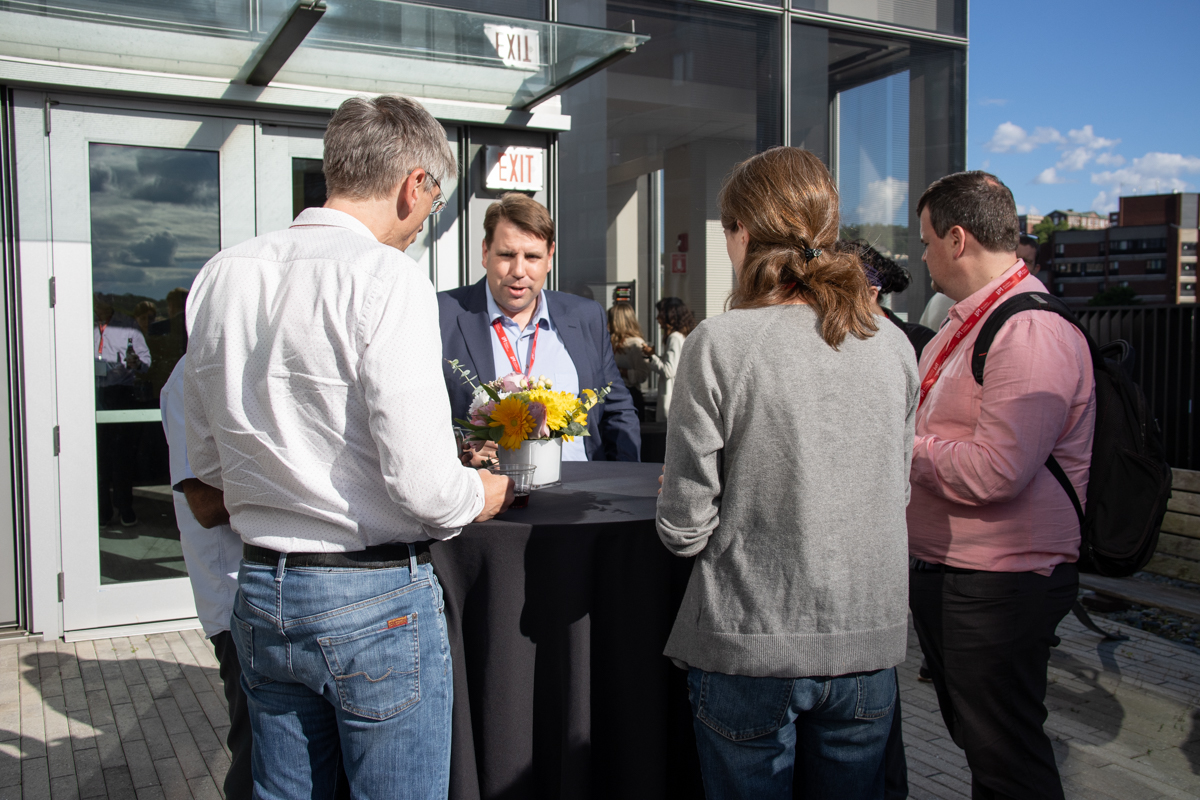 A group of conference attendees gather around a table outside.