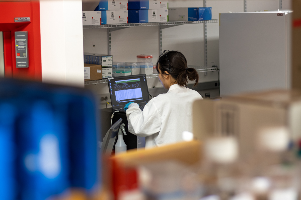 A researcher scrolls through antibody data, surrounded by biological lab supplies.