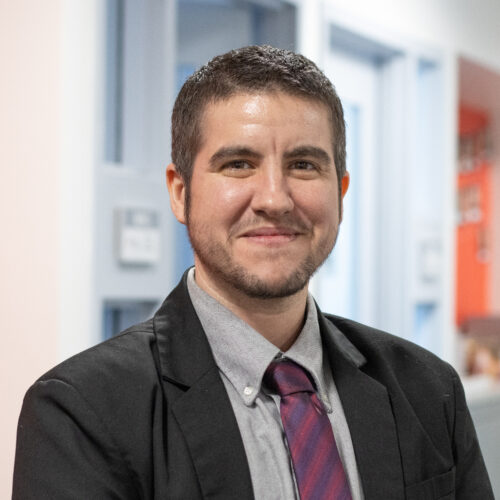 Man smiles in suit and tie.