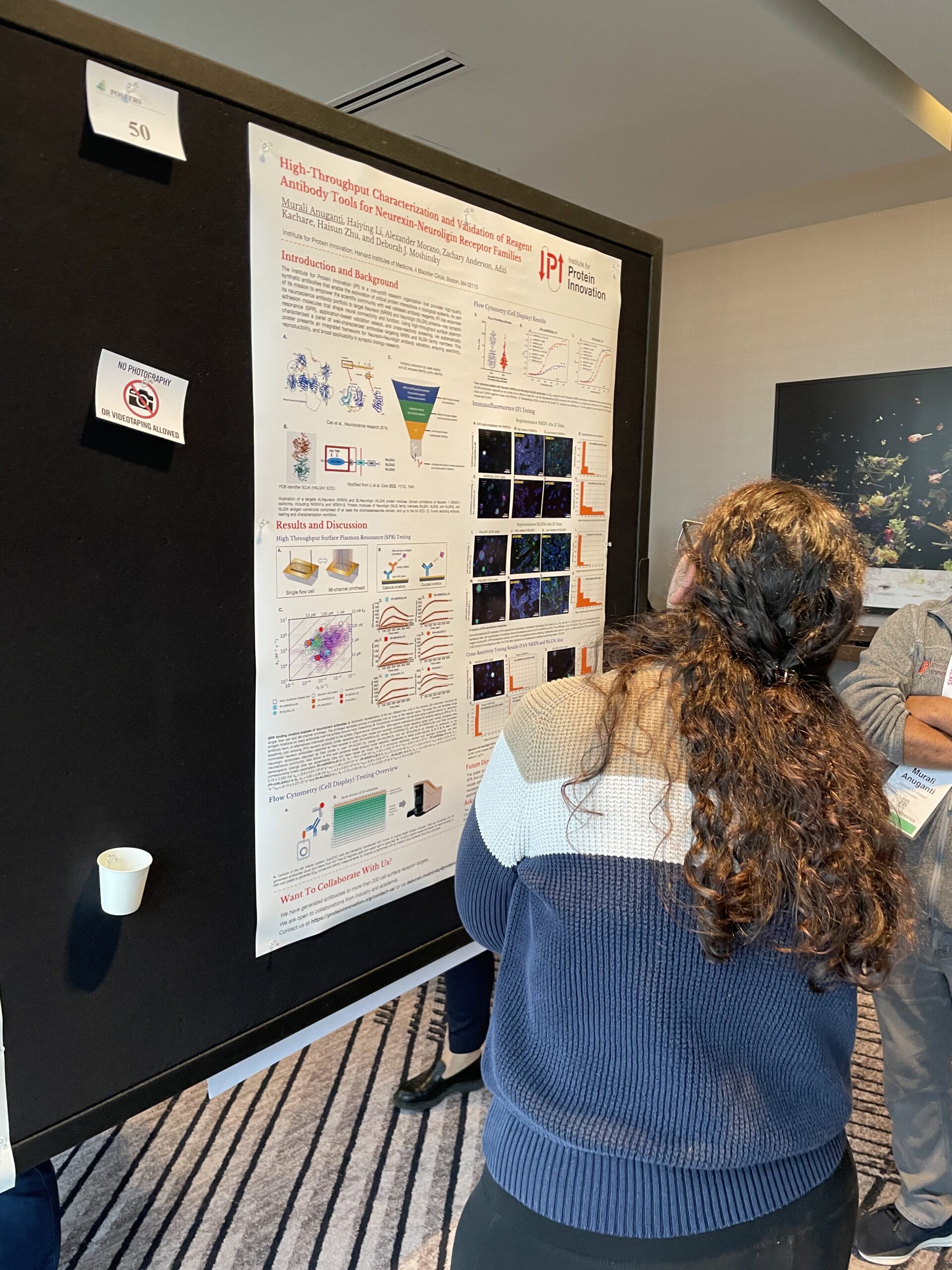 A woman looks up at a scientific poster with the IPI logo.