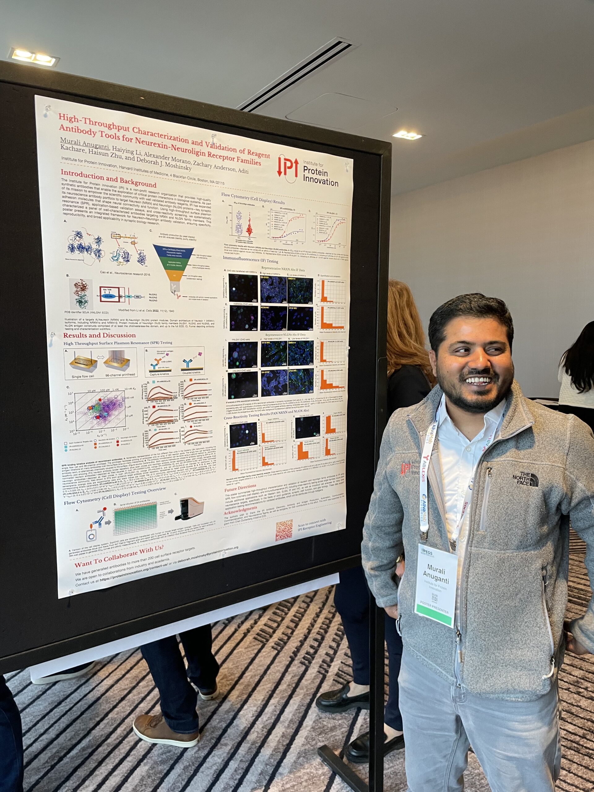 A man smiles in front of a scientific poster with the IPI logo.