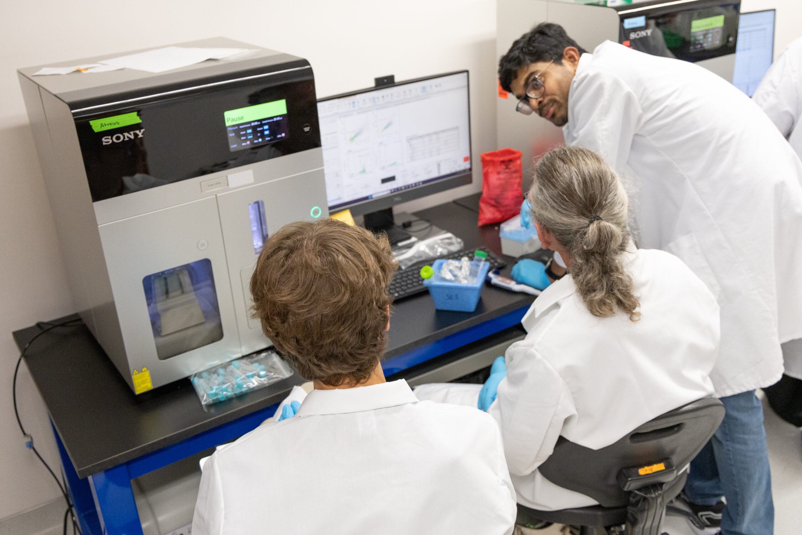 Scientist huddle over a cell sorter machine.
