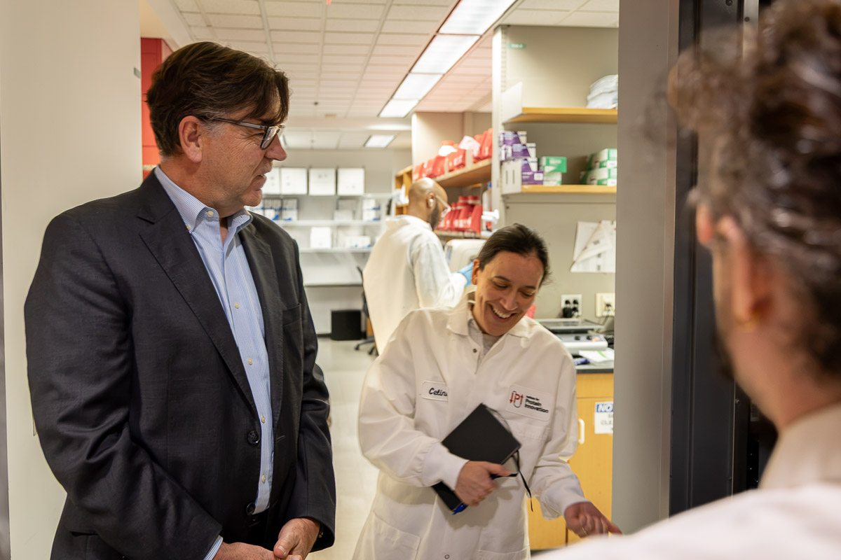 Three people stand in scientific laboratory.