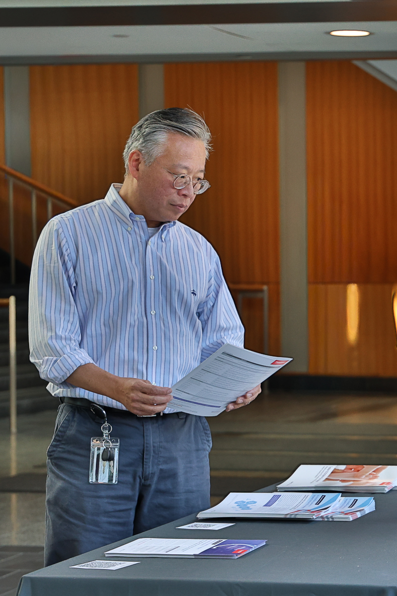 George Hong stands holds reading material.